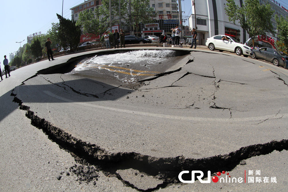 2013年5月11日，河南省商丘市，路面突然塌陷，供水管道破裂，塌陷圆坑直径近10米。图片来源：长江/CFP