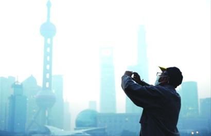 11月7日上午，一名戴口罩的老人在雾霾笼罩下的外滩拍照。当天上海遭遇五级重度污染。 /新华社