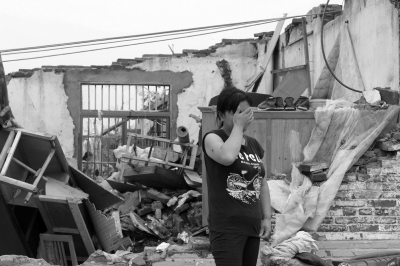 昨天，一名村民站在已成废墟的家前，掩面哭泣。