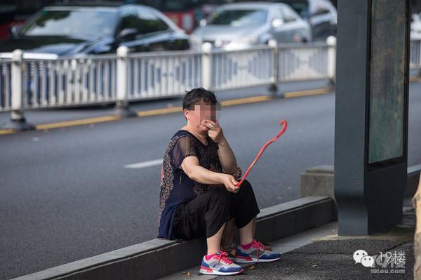 杭州大妈坐马路边抽烟让孙子学狗爬用嘴叼蛇