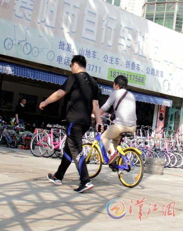 一名骑共享单车的市民从自行车批发行门前经过