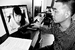 被害女孩小米(化名)的父亲梁显彬在电脑前看女儿生前的照片。