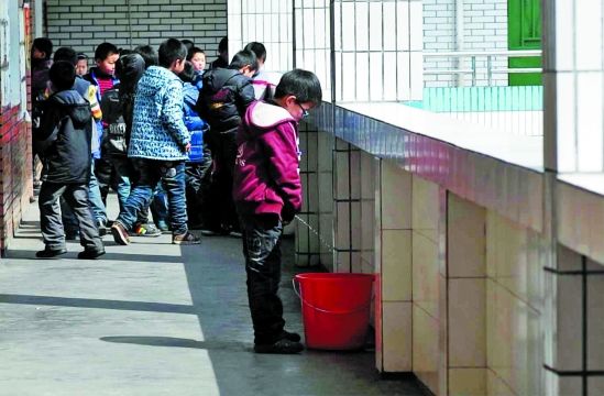 东阳一小学走廊上放着许多用来接童子尿的水桶,男孩们对此早有默契。