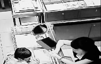 监控拍下挑戒指时,顾客悄悄把手伸向衣领处藏起钻戒。