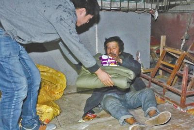   救助站工作人员冒雨为流浪者送去棉被和食物