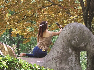 女子爬上石兽玩自拍，姿势不停变换。