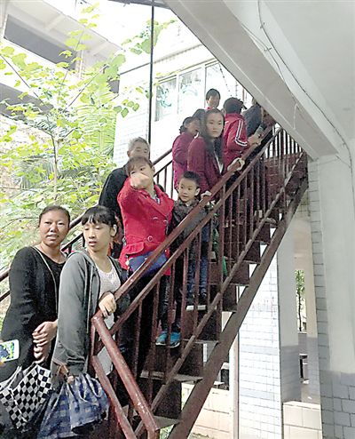 孩子和家长们被疏散到门外的楼梯上。