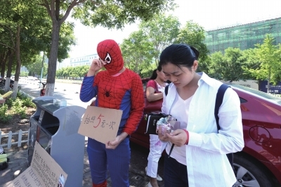何女士当街扮演“蜘蛛侠”，举牌求路人拍照，为身患噬血细胞综合征的5岁半儿子筹钱治疗。