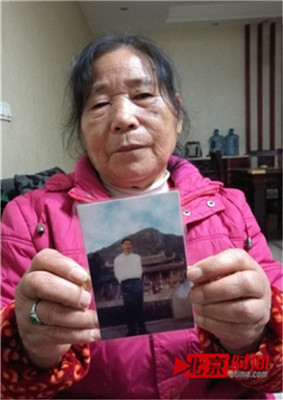 包玉贞拿着丈夫范安银的遗照。图/北京时间