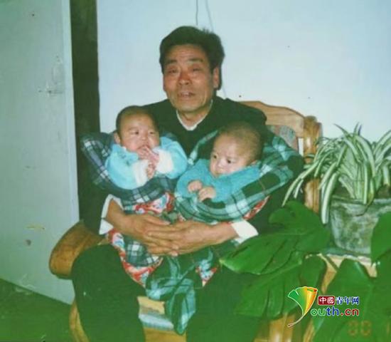 小时候的赵琦龙和双胞胎弟弟被爷爷抱着。