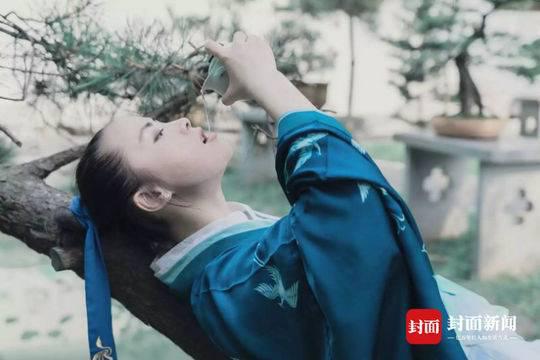 另一张照片里，姚艺身穿蓝衣，拿着酒壶，倚树自饮。