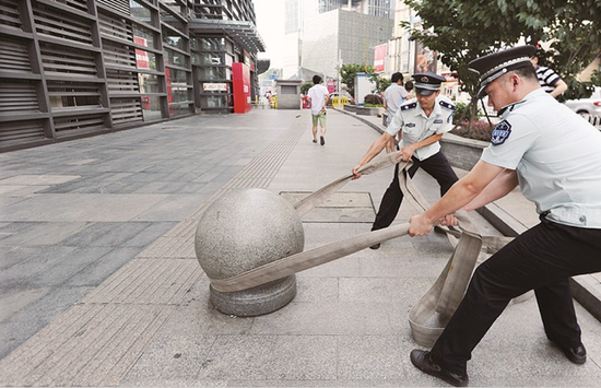 图为:城管队员清理人行道上的路障