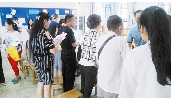 图为:一所民办初中教室内,家长排队登记 图为:一所民办初中教室内,家长排队登记