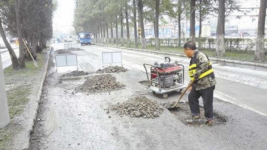 图为：道路破损严重，维修人员正进行维修