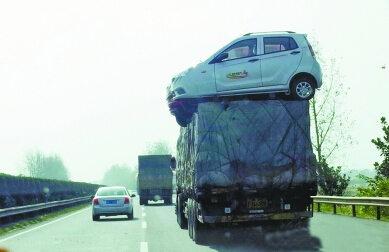 高速上满载货车“玩杂技” 车顶“趴”着4轿车