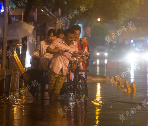 在武昌珞珈山路，因渍水严重，市民用三轮车摆渡路人。（记者宋枕涛）