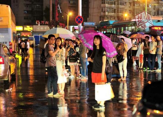 在光谷公交车站，因交通不畅，不少人在车站雨地里苦等车子。（记者李辉）