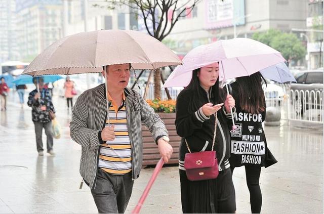 图为：昨日江城又降雨，市民外出又穿上了外套